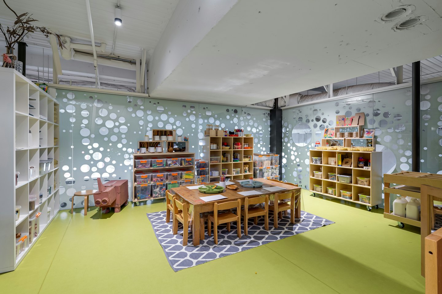 Kinderkunstkamer met houten tafels en knutselspullen op planken.
